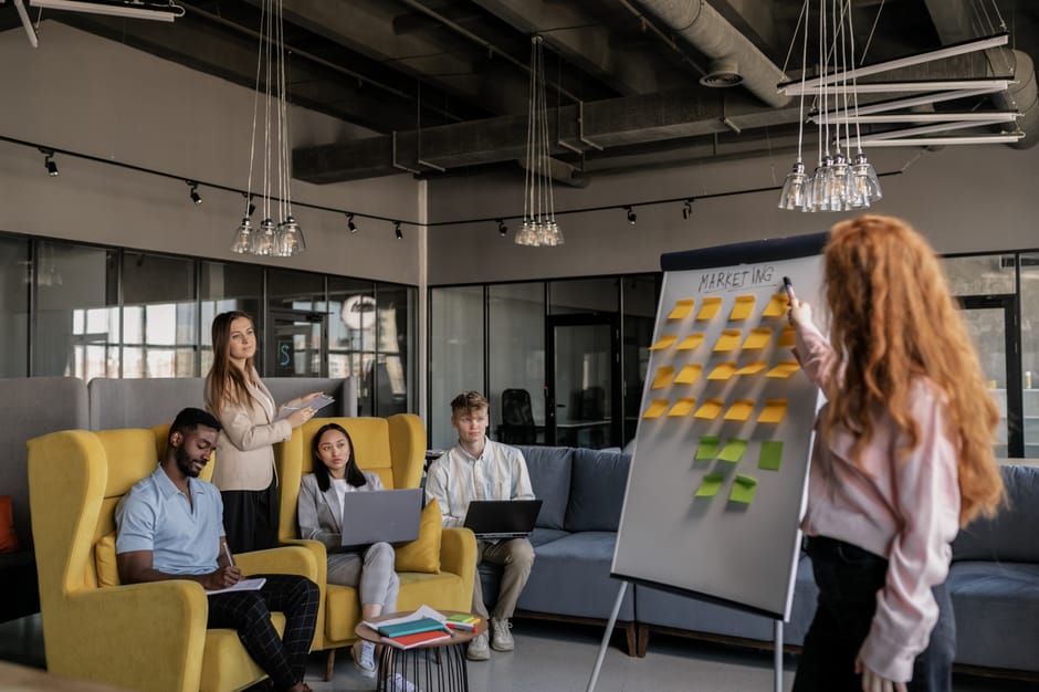 A diverse team collaborating on marketing strategy using a whiteboard with sticky notes.